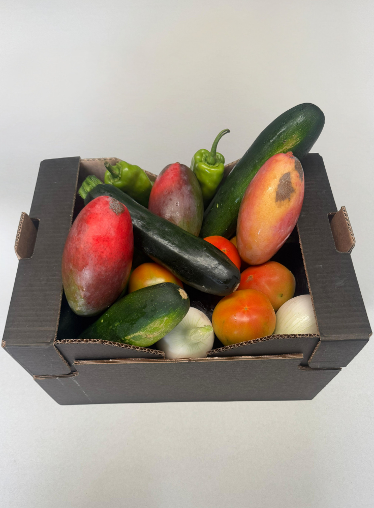 Una caja compuesta por verduras mixtas ecológicas y mangos Osteen ecológicos.