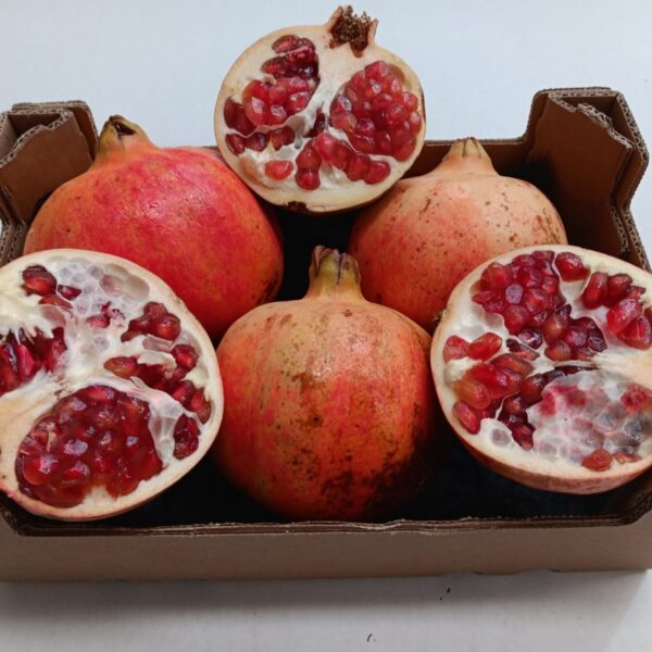 Caja de granadas ecológicas de La Axarquía, con una granada cortada por la mitad que muestra sus granos rojos y frescos.