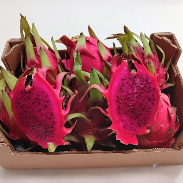 Caja de pitayas ecológicas cultivadas en Málaga por Mediterranean Farmers, con una fruta del dragón cortada por la mitad mostrando su pulpa natural.